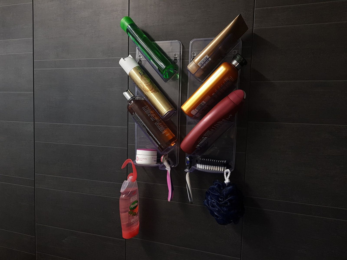 Two ShowerGem shower caddies holding bottles on a dark tiled shower wall